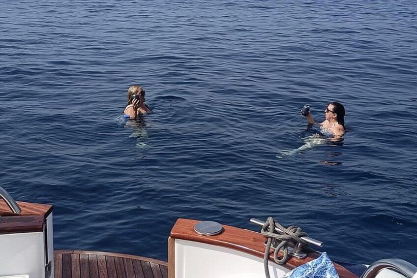 Two people swimming in the ocean from a boat. 3