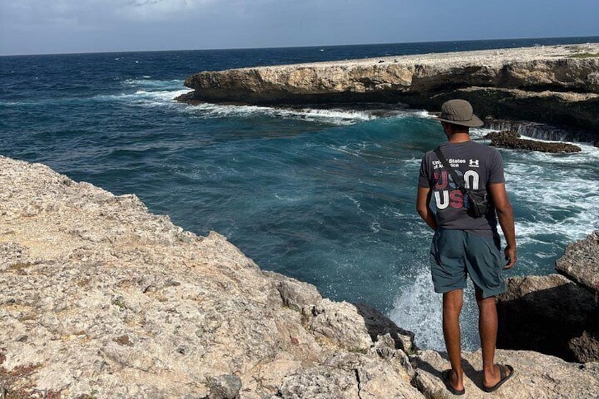 Une personne se tient debout sur un promontoire rocheux, d’où elle a une vue sur l’océan. 4