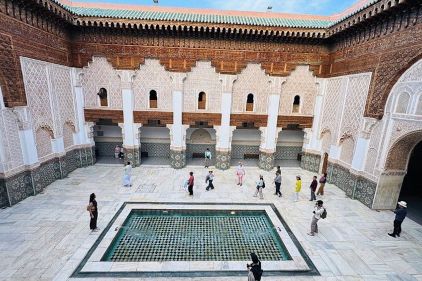 A courtyard with a fountain, arches, and people walking. 4