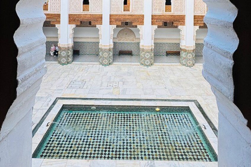 A courtyard with a tiled swimming pool, a wooden balcony, and intricate tile patterns on the walls. 5