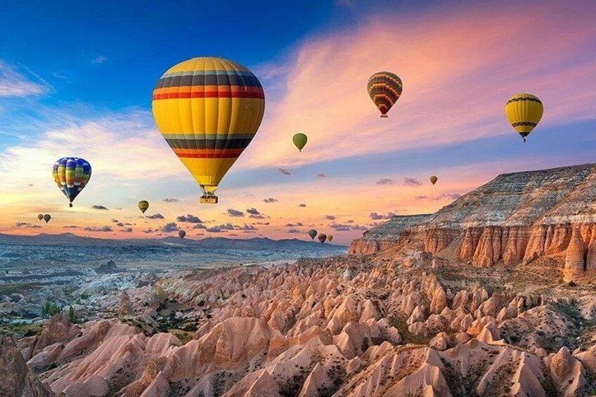 Hot air balloons over a rocky landscape at sunset. 1