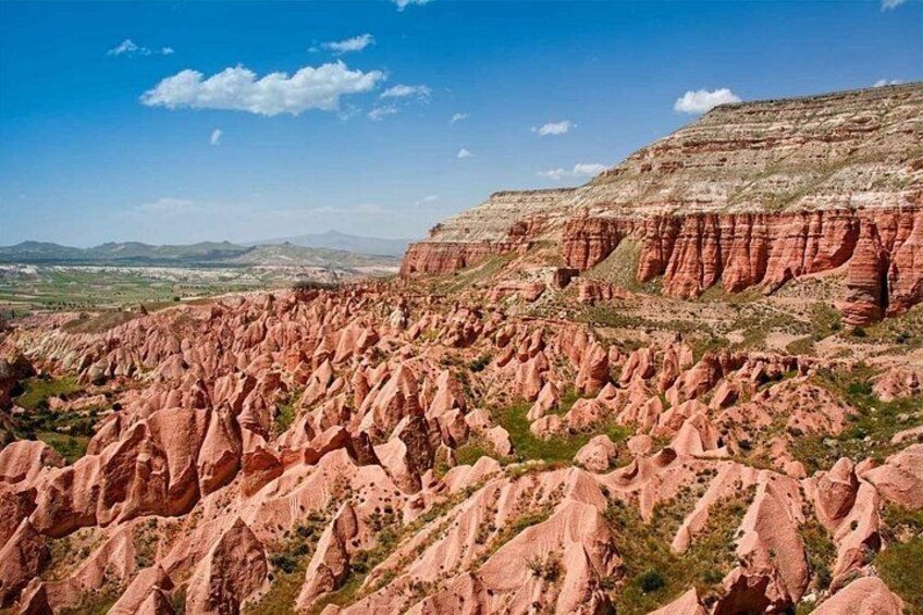 A vast red rock landscape with layered formations and sparse vegetation. 4