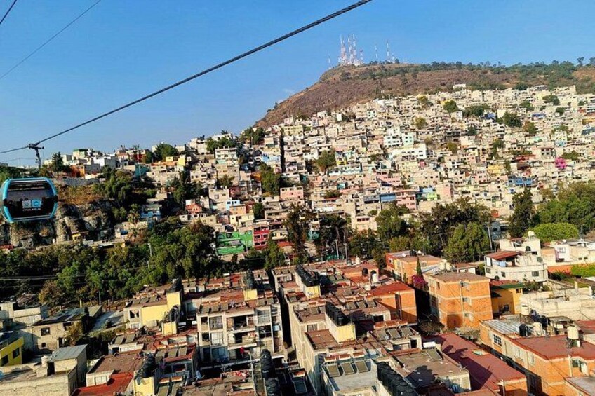 Un paisaje urbano en una ladera densamente poblada, con un teleférico en primer plano. 4
