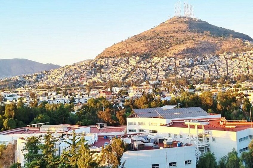Un paisaje urbano con una colina destacada, edificios residenciales y algunos árboles. 2