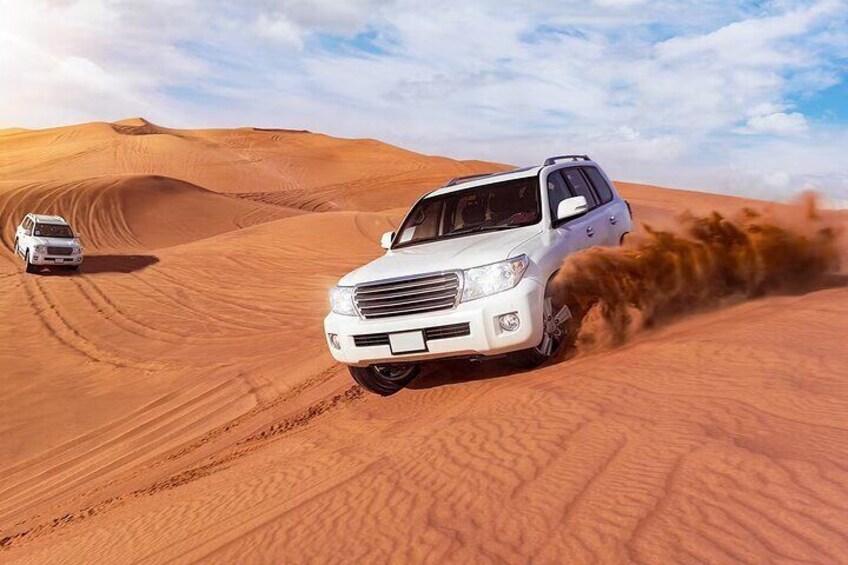 A white SUV driving through a desert with sand dunes in the background. 4