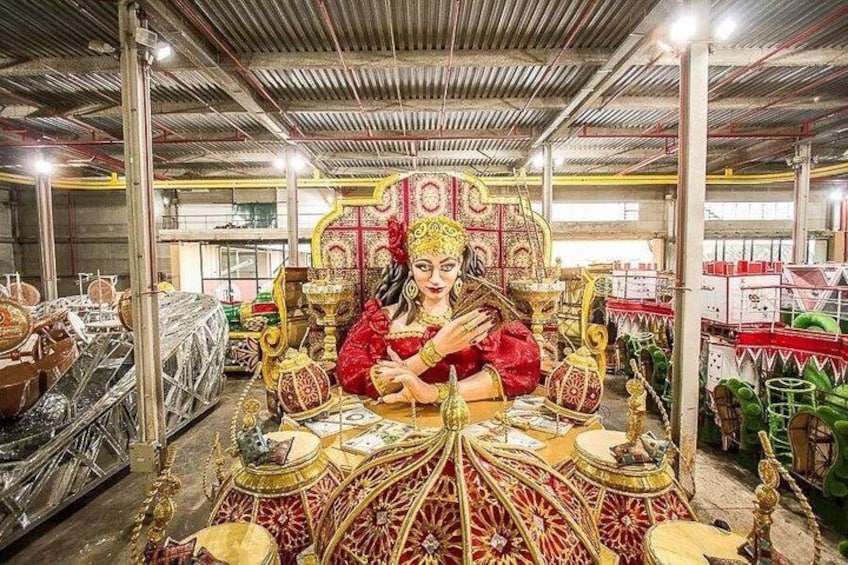 A person seated on an ornate throne in a workshop with machinery and tools in the background. 5