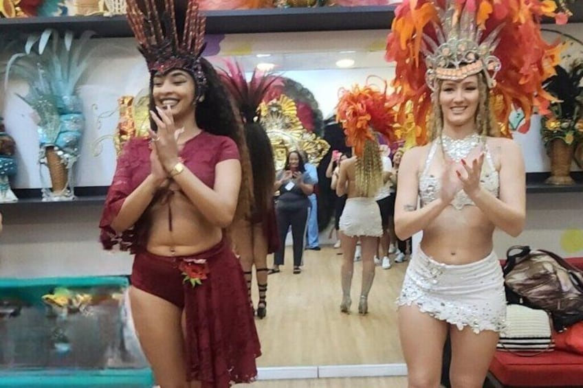 Two individuals in traditional costumes with elaborate headdresses, standing in a room with decorative elements and a visible pool in the background. 3