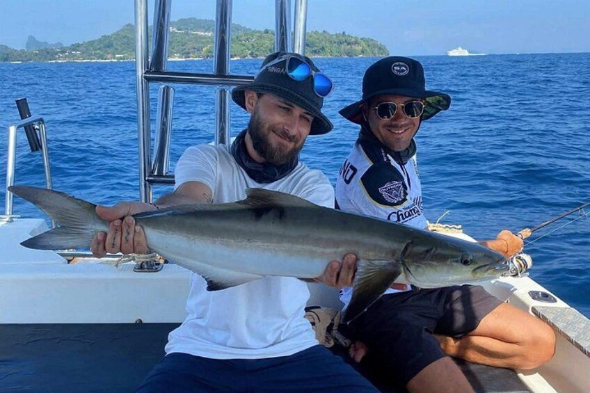 Two people on a boat holding a large fish. 1