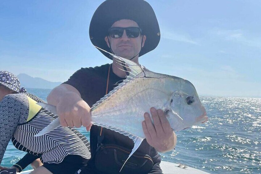 A person holding a fish on a boat with a clear sky and water in the background. 3