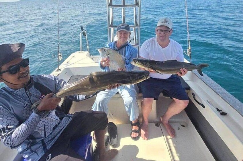 Three people on a boat holding fish. 2