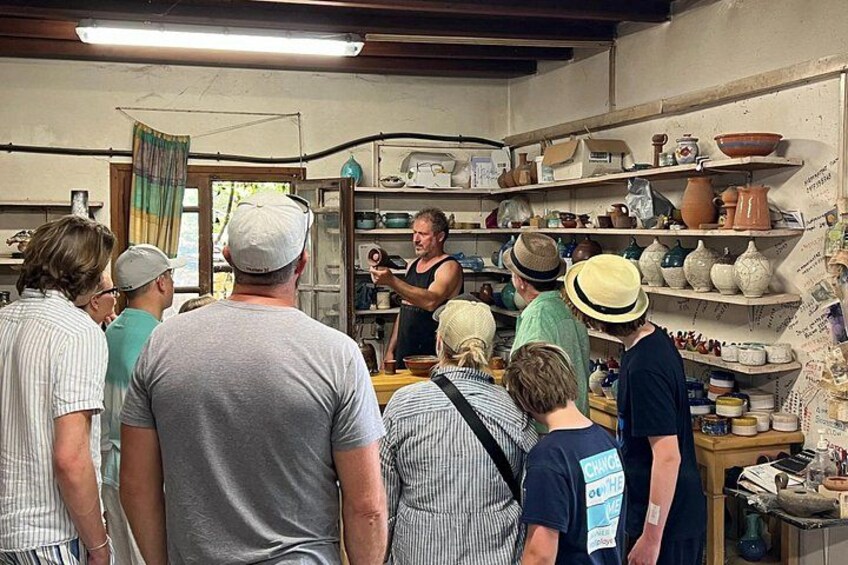 Un atelier de poterie où des personnes observent une démonstration. 4
