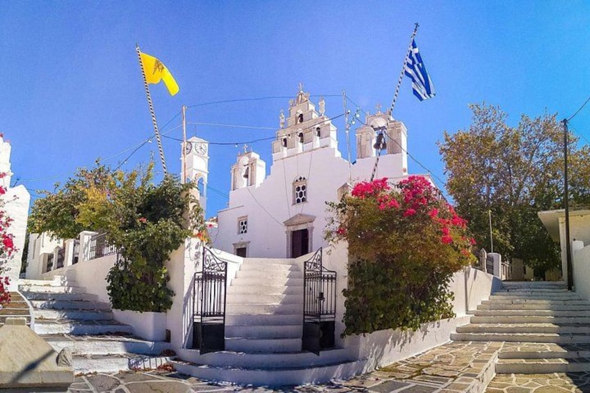 A white building with a bell tower, steps leading up to it, and two flags. 2