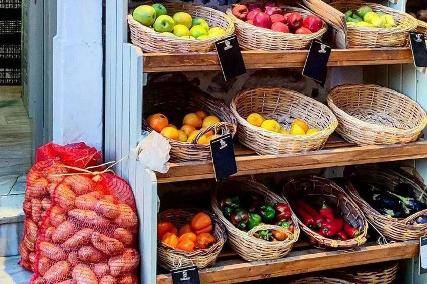 A fruit stand with baskets of apples, oranges, and other fruits. 2