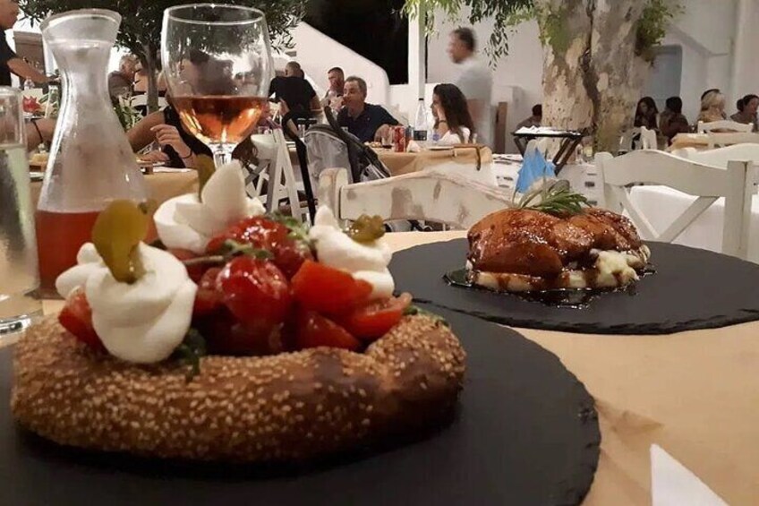 Ett matbord med två tallrikar mat, en flaska sås och ett glas vin. 4