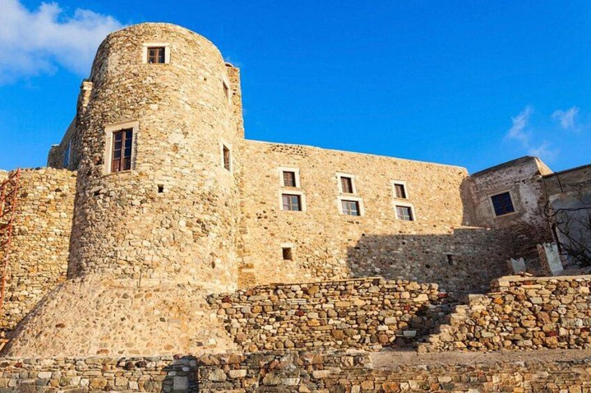 Un château de pierre doté d’une tour ronde, d’une vaste cour ouverte et surplombé d’un ciel bleu azur. 2