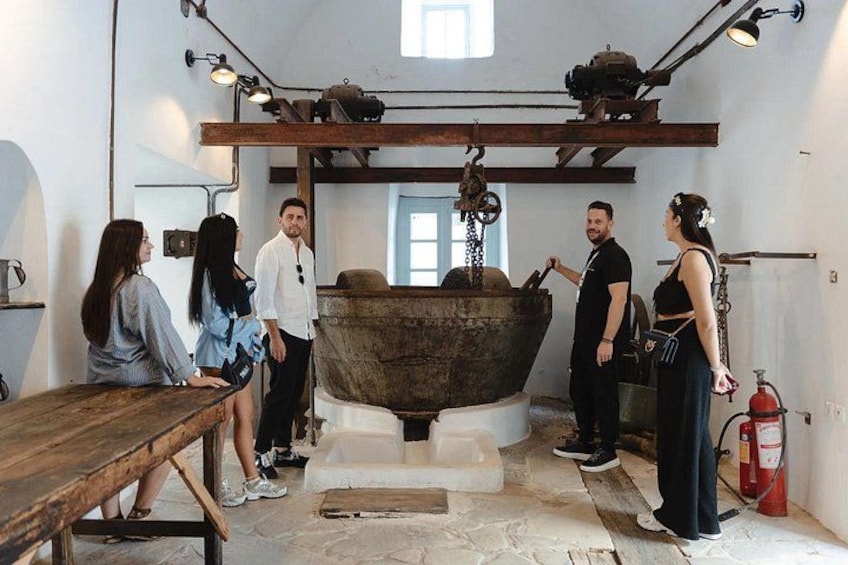 A group of people in a workshop with large machinery and a wooden table. 1
