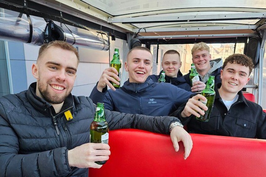 Un gruppo di persone su un veicolo rosso, che tiene in mano bottiglie verdi. 5