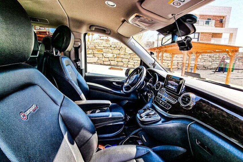 Een auto interieur met zwarte lederen stoelen, een stuurwiel, een dashboard met een scherm en een versnellingspook. 3