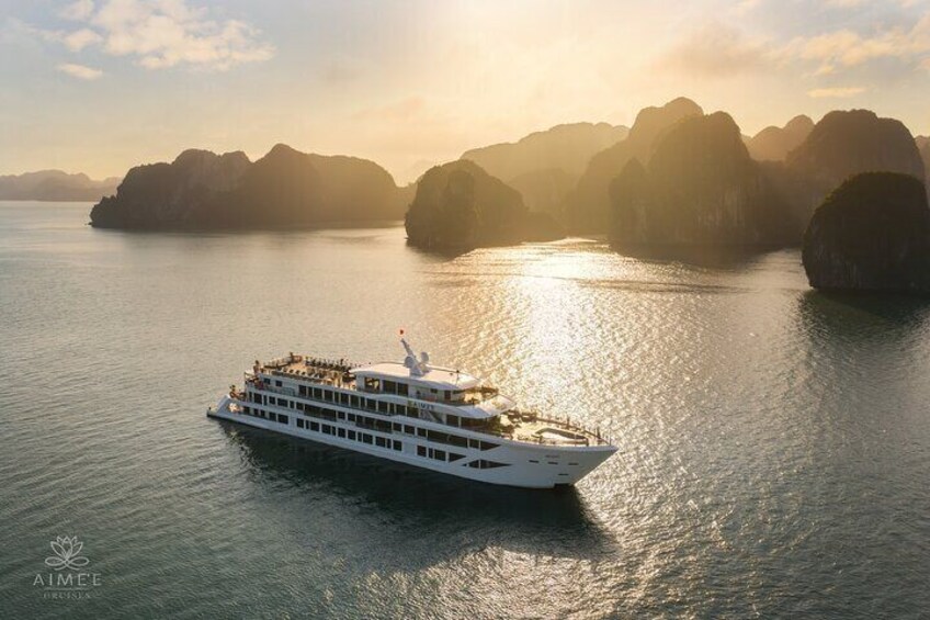 A white cruise ship sailing in a body of water with large rock formations in the background. 1
