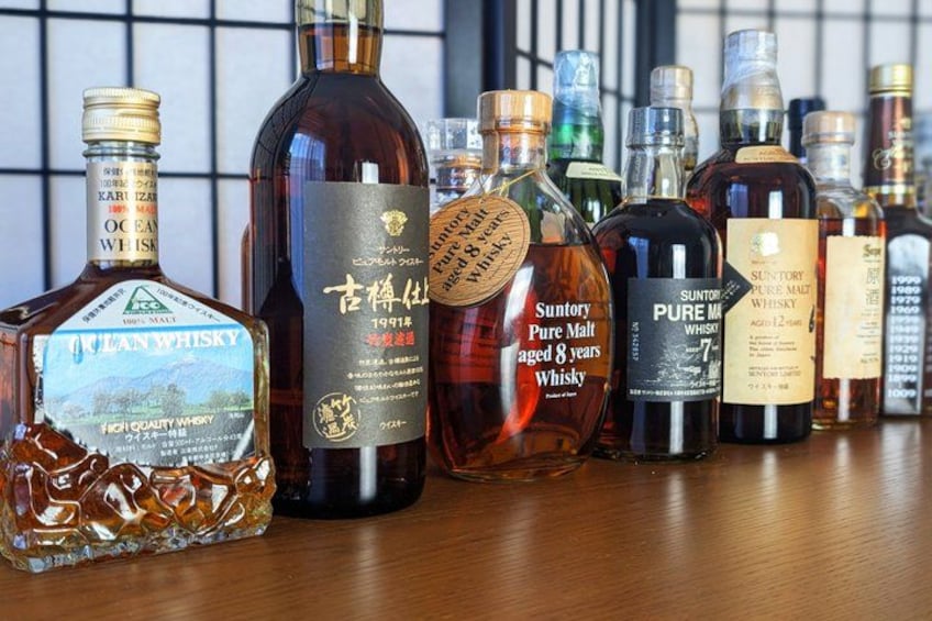 A variety of whiskey bottles on a wooden surface. 2