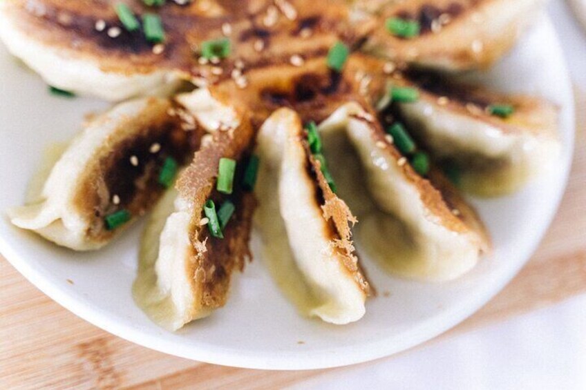 A plate of dumplings garnished with sesame seeds and chopped green onions. 2