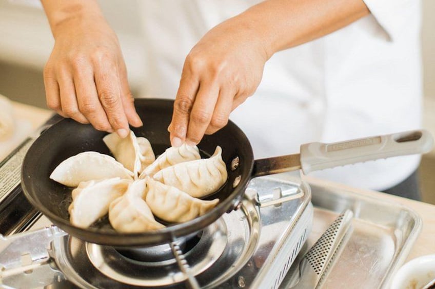 En person laver dumplings i en pande. 2