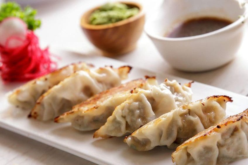 En tallerken med dumplings, dyppesauce og syltede grøntsager. 3