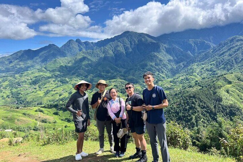 A group of people standing on a hill with a mountainous landscape in the background. 1