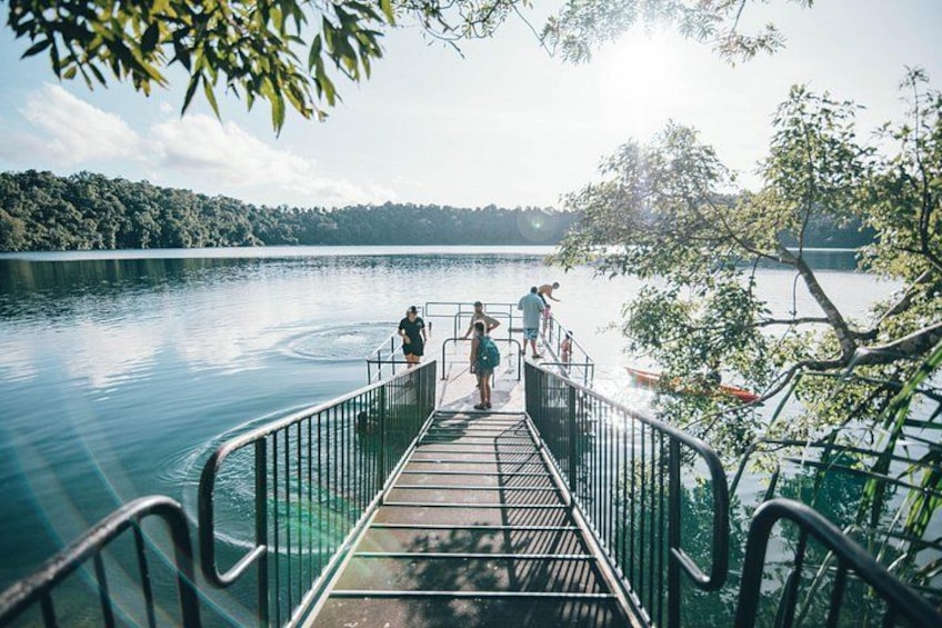 A wooden pier extending into a lake, surrounded by trees and a clear sky. 2
