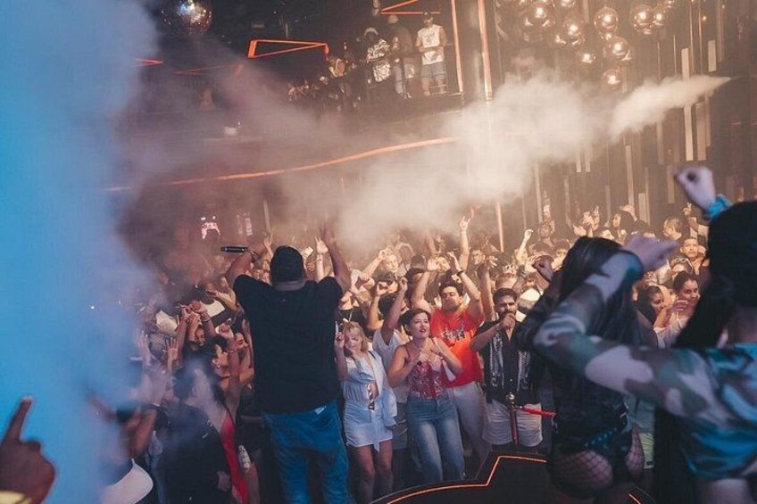 Un evento multitudinario en interior, con escenario y efectos de humo. 2