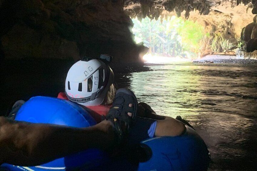 Una persona en una balsa azul con casco blanco, navegando un río dentro de una cueva. 1