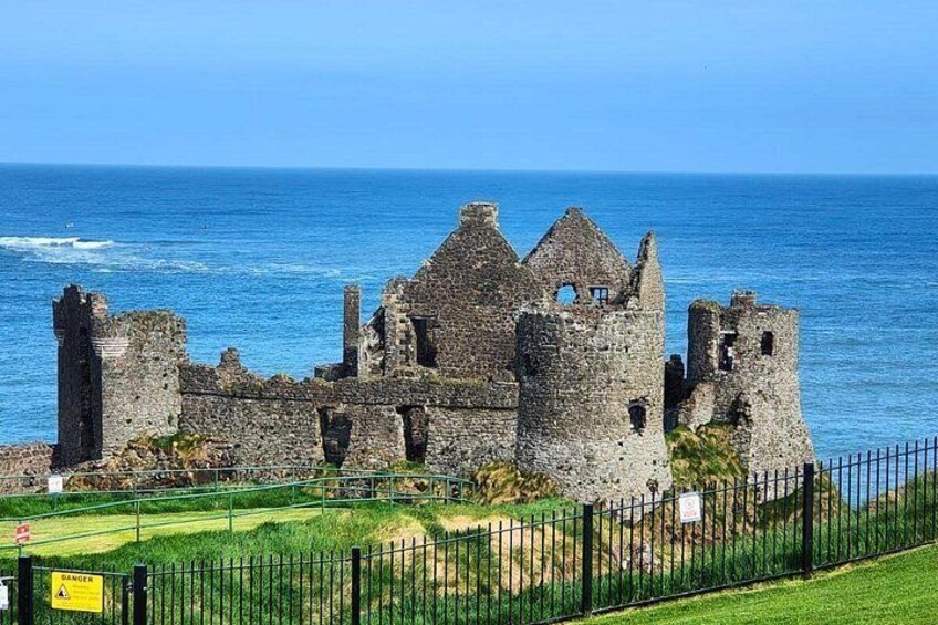 A historic stone castle by the sea with a clear sky. 1