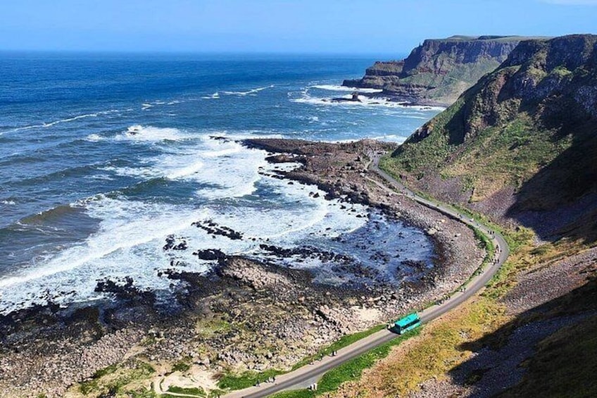 A coastal road with a bus, cliffs, and the ocean. 4