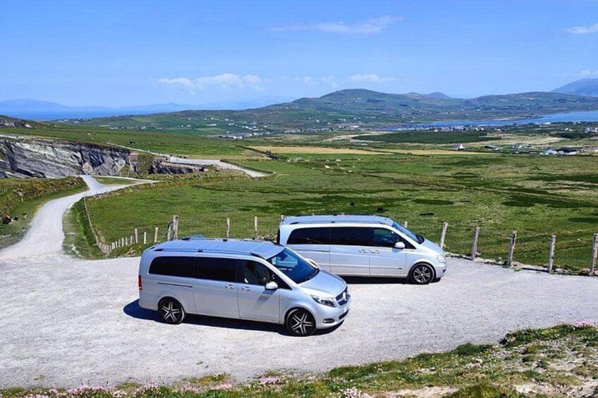 Twee witte auto's staan op een grindweg met een mooi landschap op de achtergrond. 4