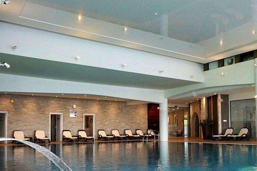 An indoor swimming pool with lounge chairs and a brick wall. 2