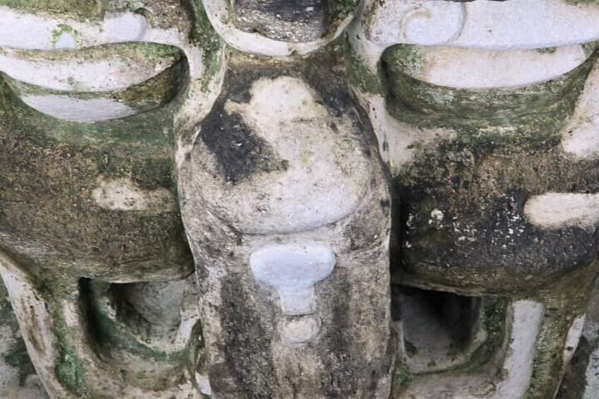En väderbiten stenskulptur med inristade figurer och ett hjärtformat motiv i mitten. 2