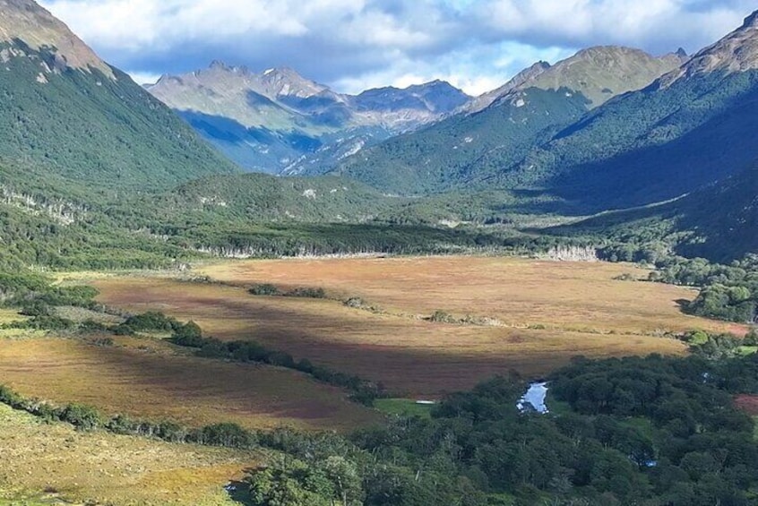 Een bergachtig landschap met een rivier, groene valleien en verre bergtoppen. 5