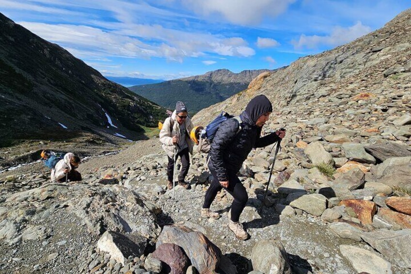 Wandelaars op een rotsachtig bergpad met een waterval op de achtergrond. 4