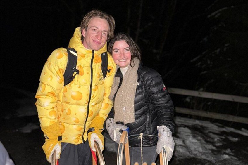 Two people in winter clothing, one in a yellow puffer jacket and the other in a black jacket, standing outdoors with snow on the ground. 4
