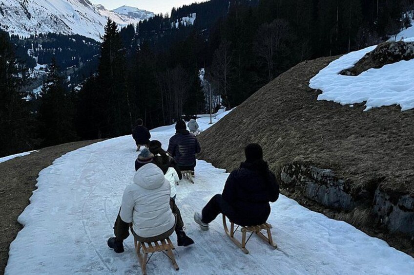 A group of people sitting on sleds on a snow-covered slope. 3