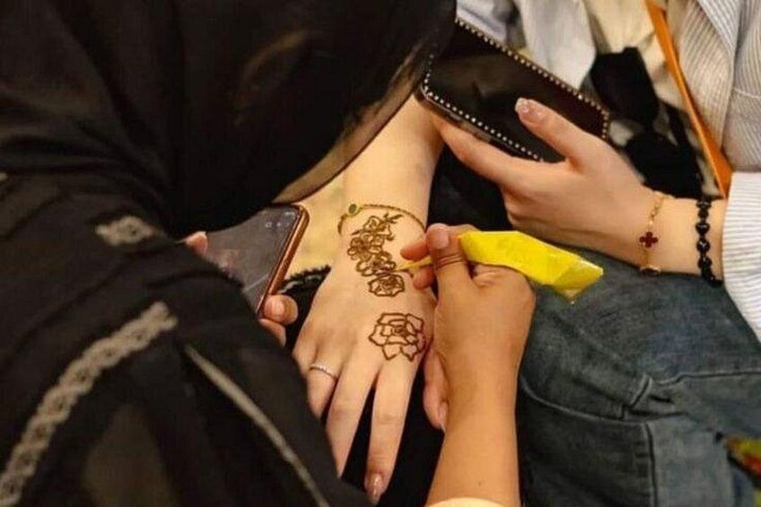 Eine Person trägt Henna-Malerei auf die Hand einer anderen Person auf. 3
