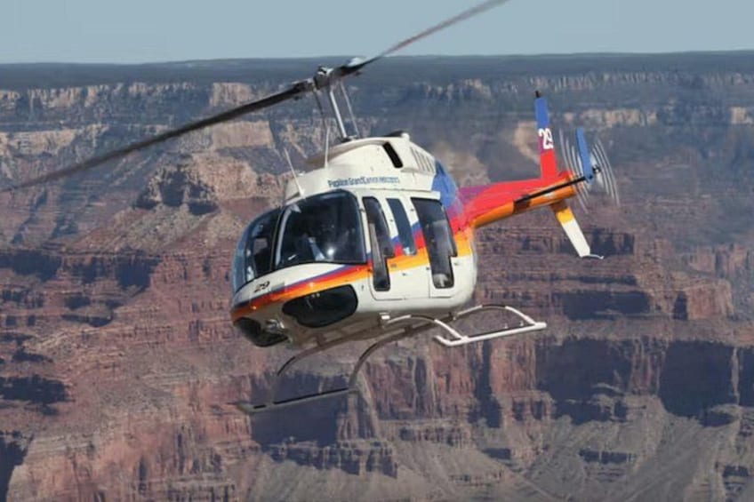 A helicopter flying over a canyon with a rugged landscape. 5