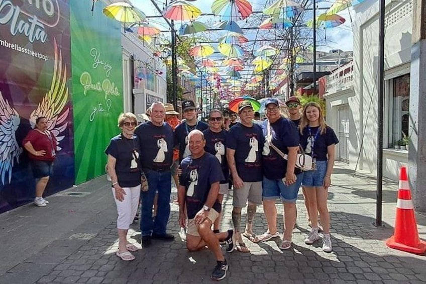 A group of people posing in front of a colorful umbrella installation. 2