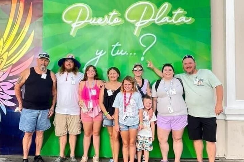A group of people standing in front of a green wall with the text 'Puerto Plata y tu...?' 2