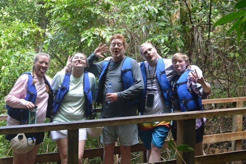 A group of people on a wooden bridge in a forested area. 3
