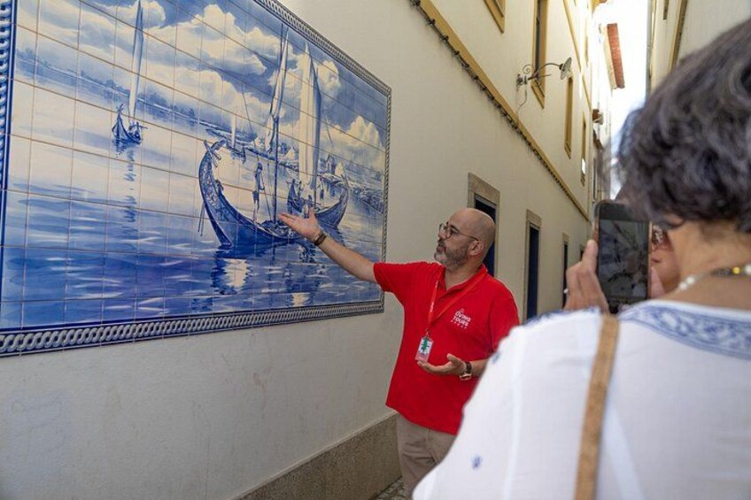 Un muro rivestito di piastrelle con una scena marina, una persona che indica e un'altra che scatta una foto. 2