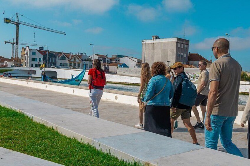 Un paseo marítimo con gente caminando, una góndola y edificios al fondo. 2