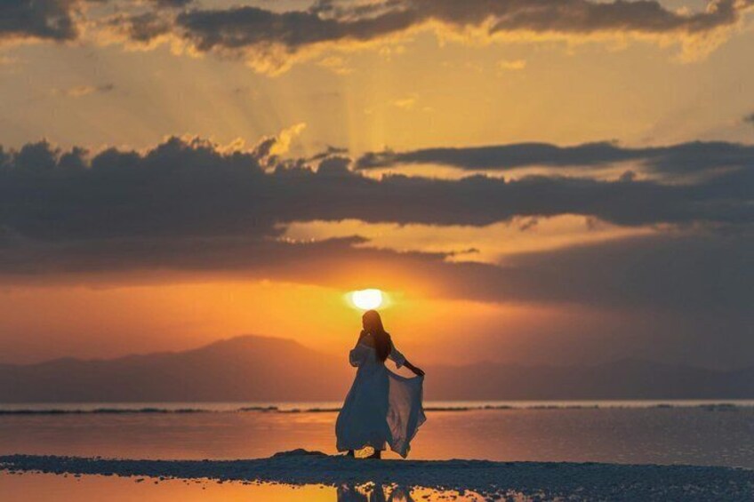 Eine Person geht am Strand, während die Sonne im Hintergrund untergeht. 4