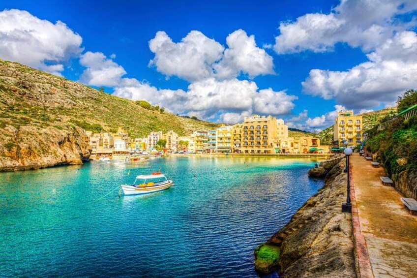 A coastal town with buildings, a boat, and clear blue water. 3