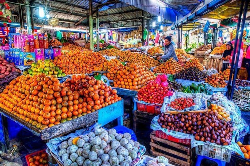 A bustling fruit market with various fruits like oranges, apples, and bananas displayed in stalls. 5